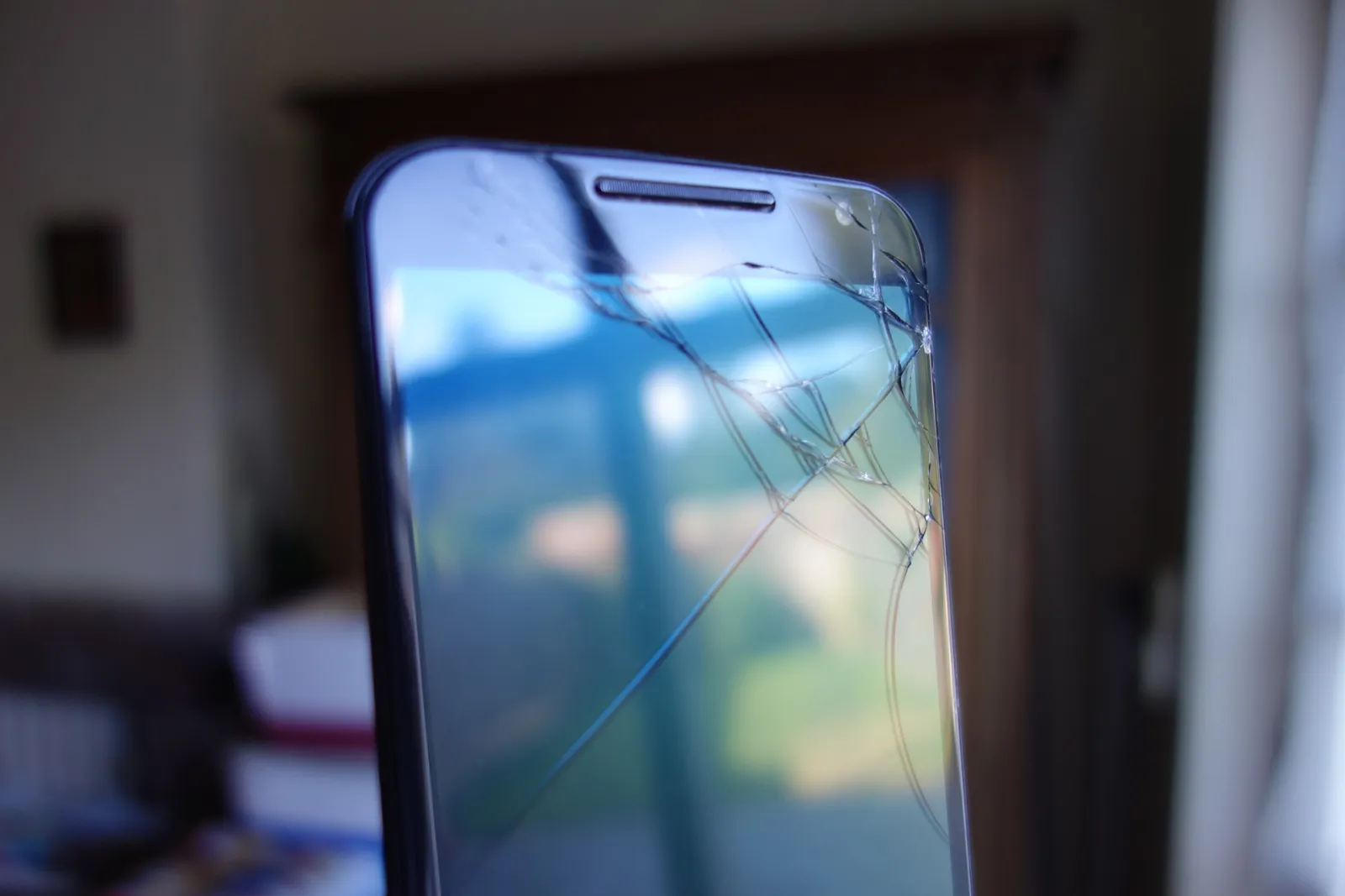 Close-up of a smartphone with a badly cracked glass screen