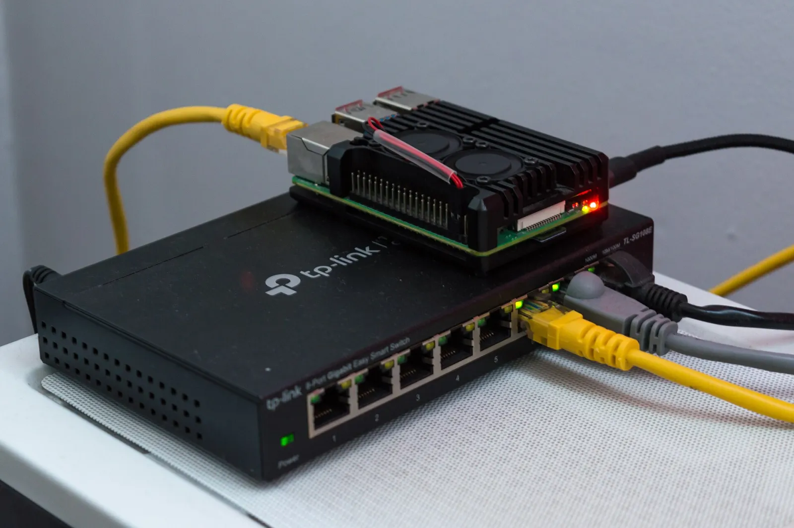 Raspberry Pi 4 in a black aluminium case with fans sitting on a TP-Link network switch