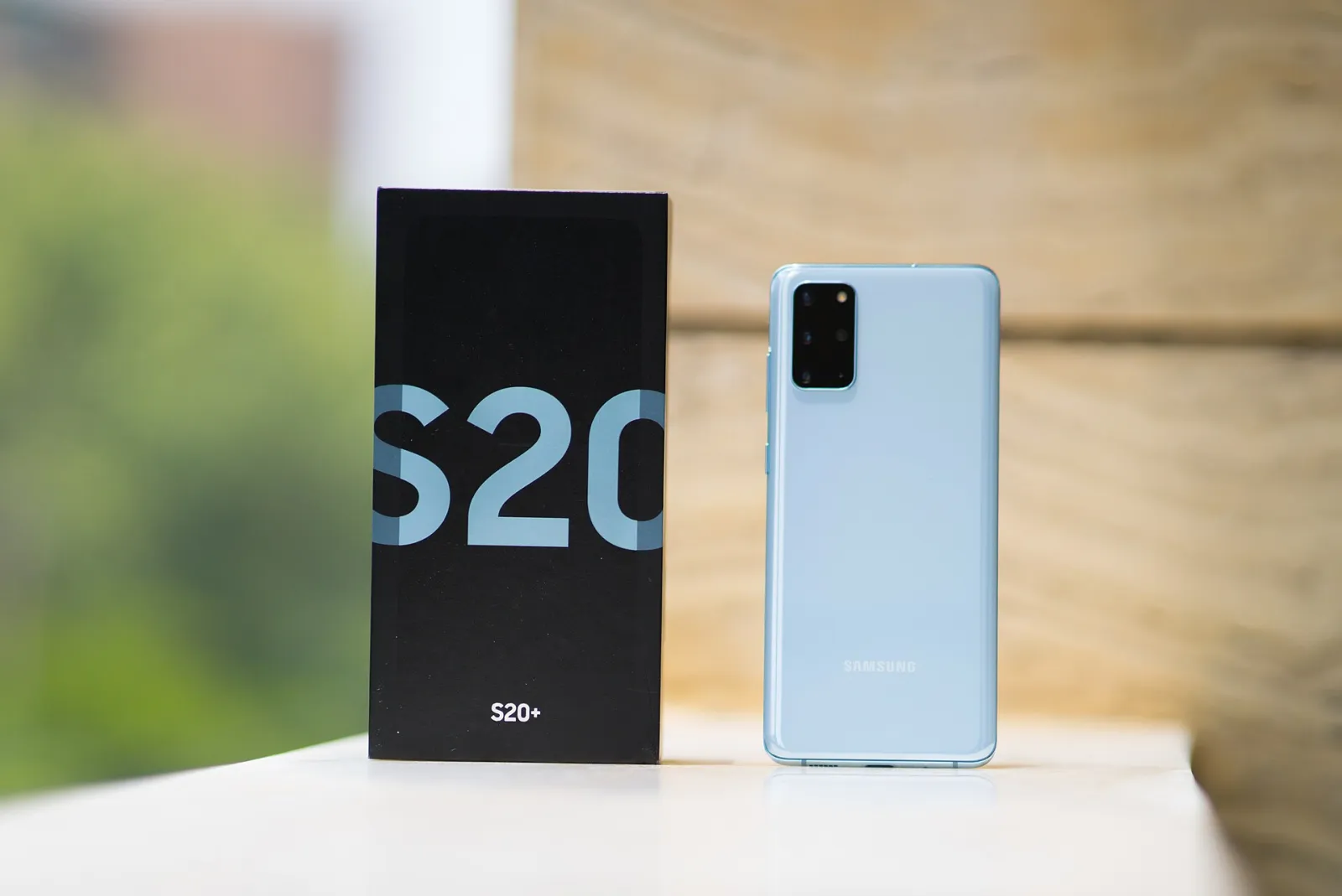 Samsung Galaxy S20+ smartphone in Cloud Blue standing next to its retail box